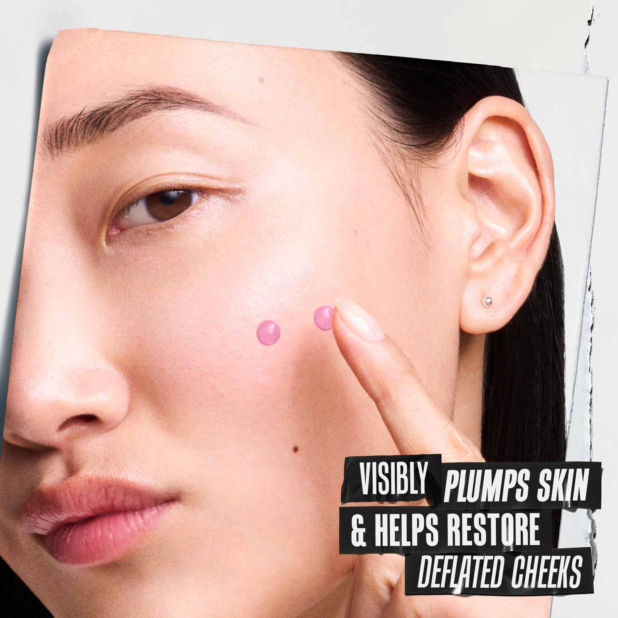 Close-up of a model's face with two pink serum drops on her cheek. Text reads: "VISIBLY PLUMPS SKIN & HELPS RESTORE DEFLATED CHEEKS."​