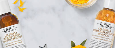 Kiehl’s Calendula Collection featuring Deep Cleansing Foaming Face Wash, Herbal-Extract Toner, and Serum-Infused Water Cream on floral background